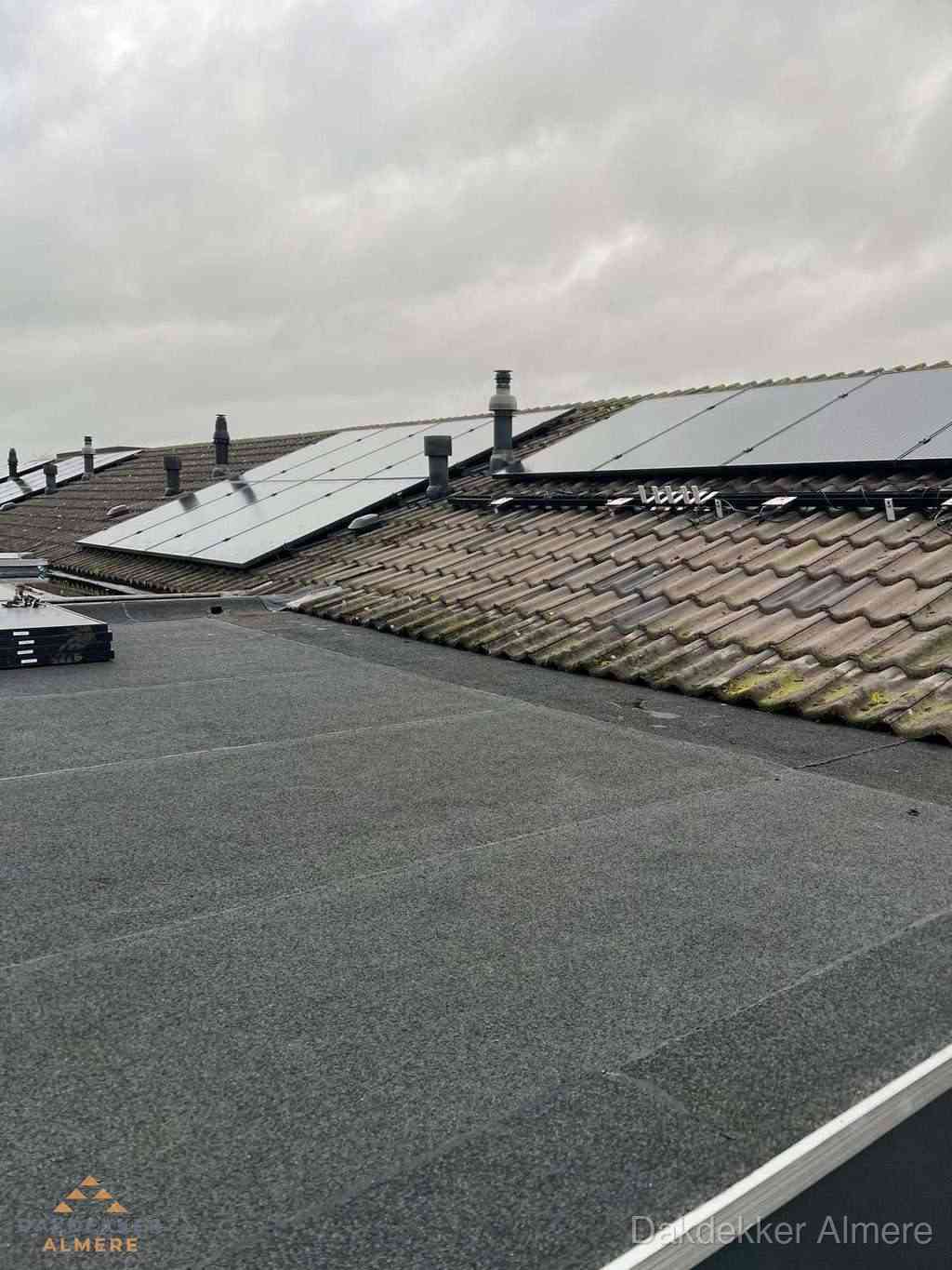 Plat dak inspectie met bitumen bedekking naast schuin pannendak in Almere
