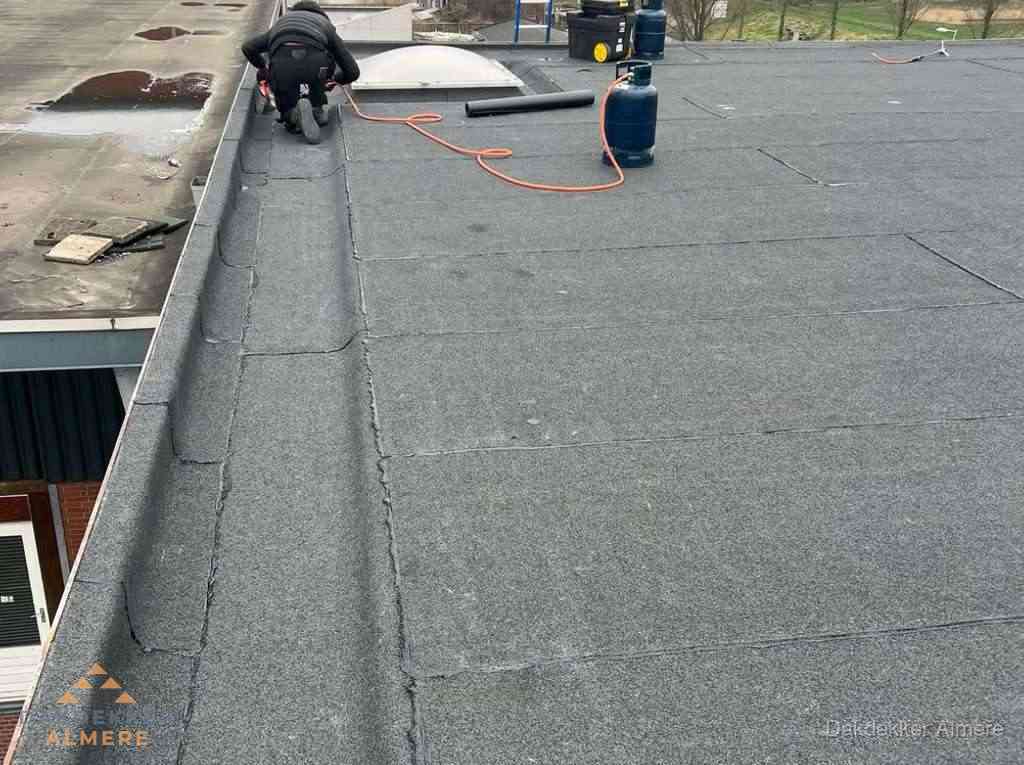 Dakdekker repareert bitumen dakbedekking op groot plat dak in Almere