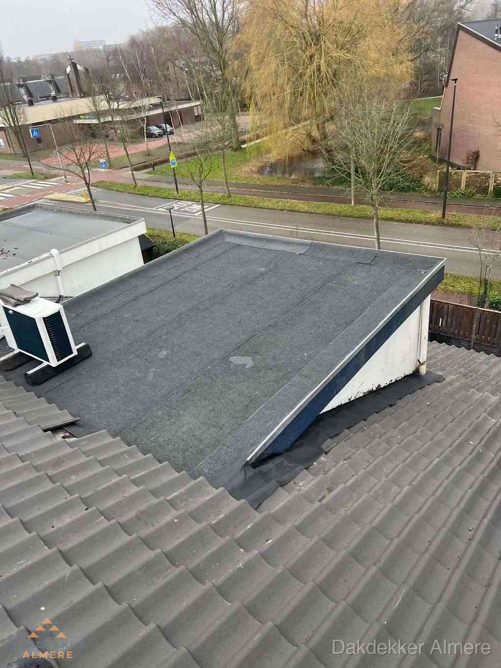 Plat dak met bitumen dakbedekking naast schuin pannendak in Almere